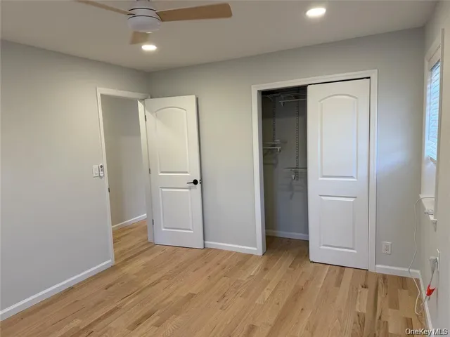 an empty room with wooden floor and a ceiling fan