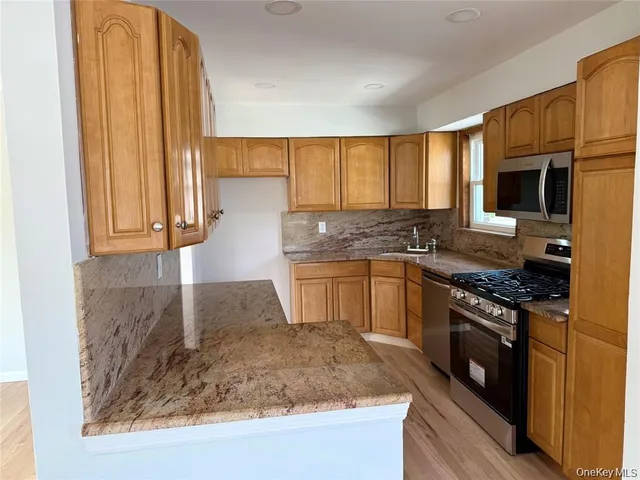 a kitchen with stainless steel appliances granite countertop a stove a sink and a microwave