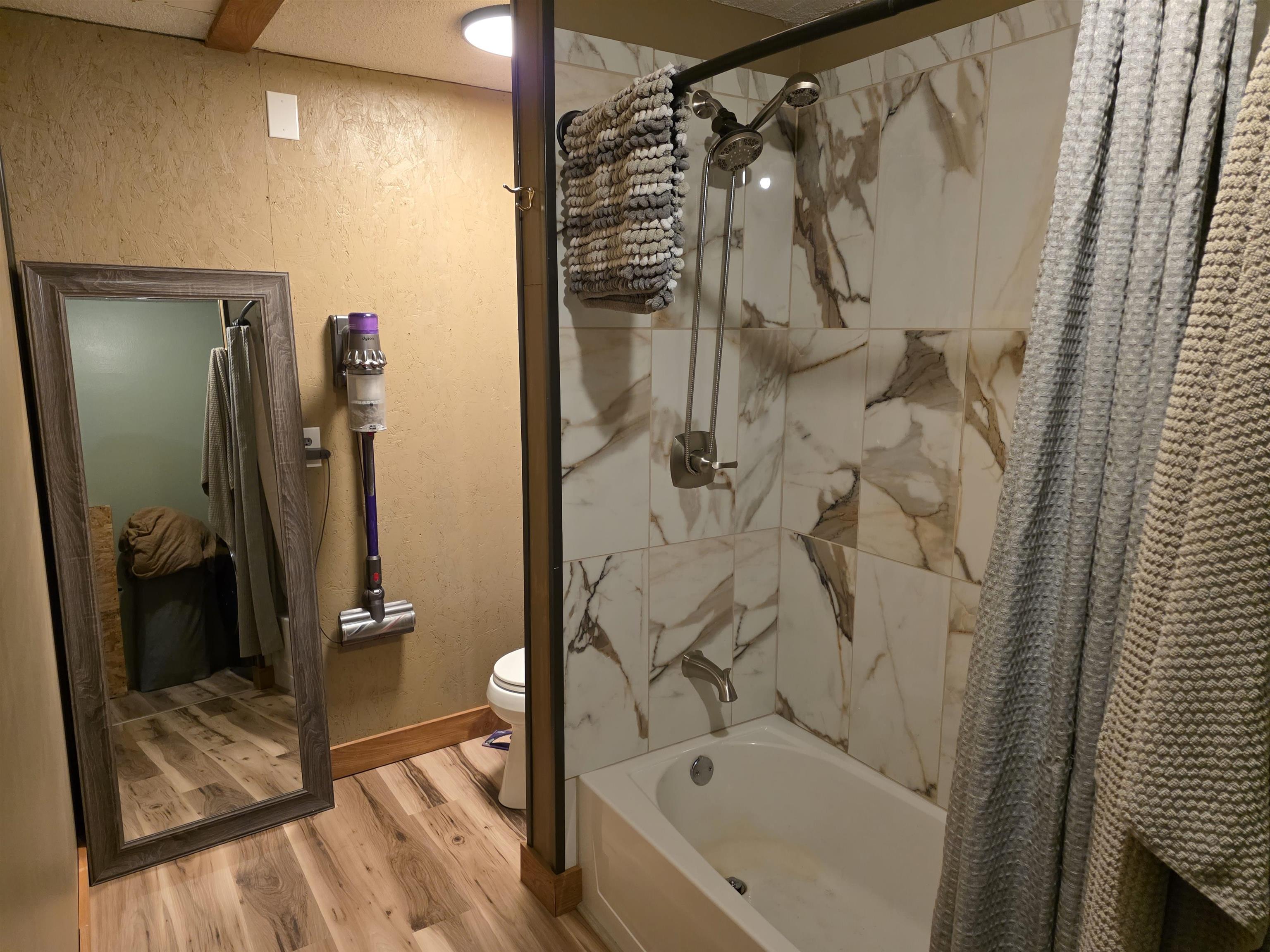 6821 Barrett Road Chisholm, MN 55719 - Photo 11 of 34 Full bath featuring wood finished floors, shower / tub combo, and a textured wall