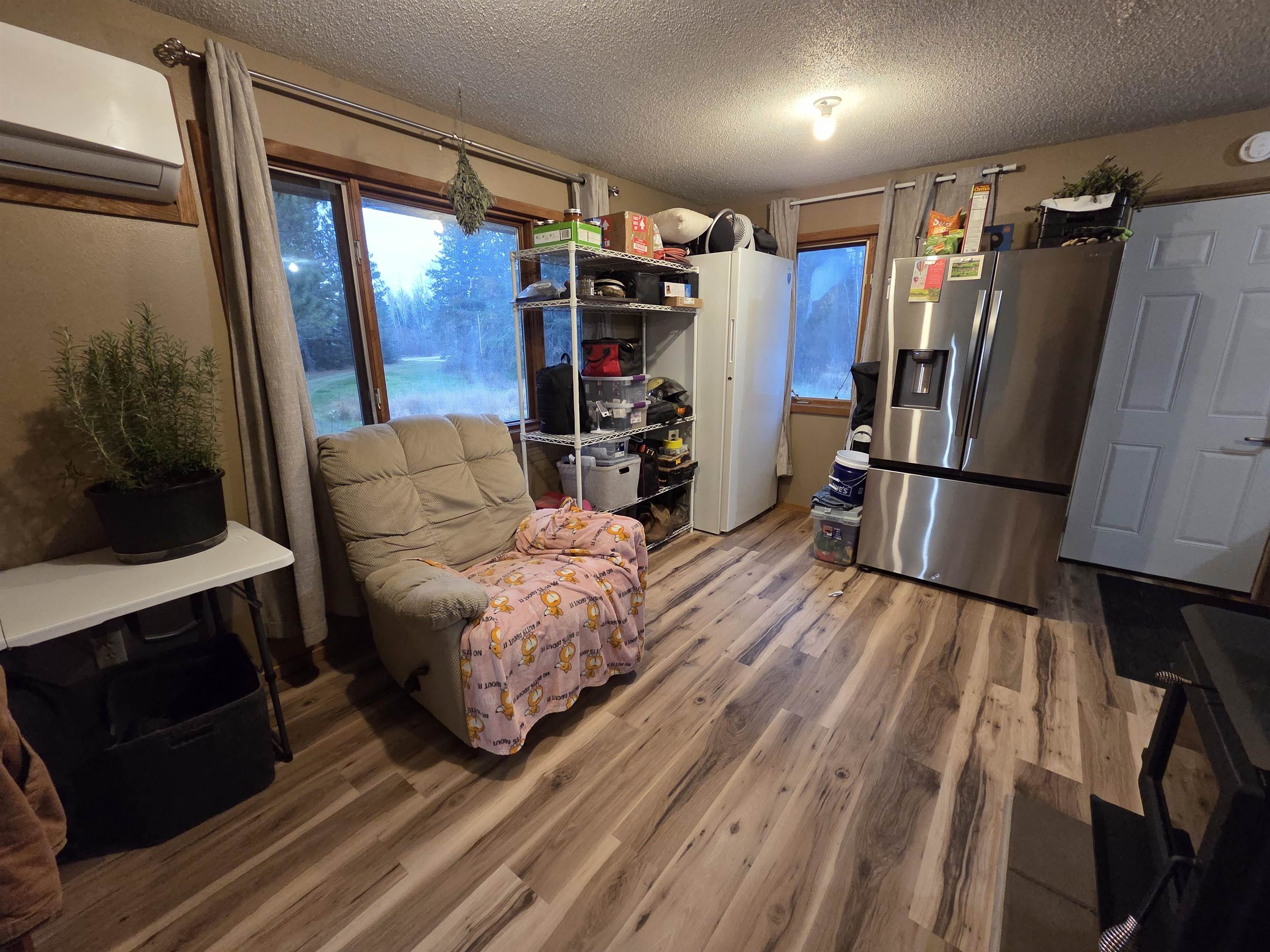 6821 Barrett Road Chisholm, MN 55719 - Photo 4 of 34 Sitting room featuring wood finished floors, a wall mounted air conditioner, a textured ceiling, and plenty of natural light