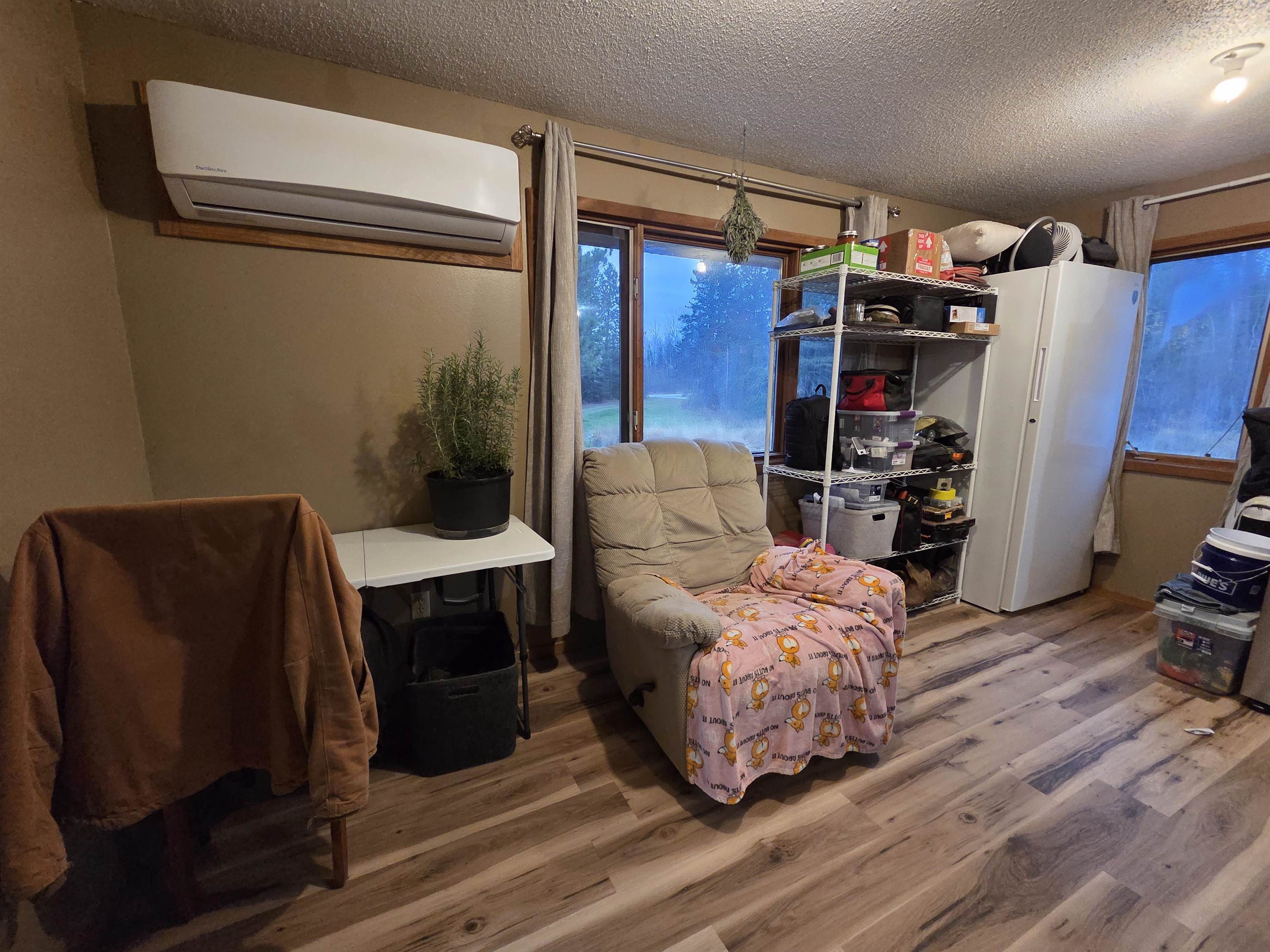 6821 Barrett Road Chisholm, MN 55719 - Photo 5 of 34 Living area featuring wood finished floors, a textured ceiling, and a wall mounted AC