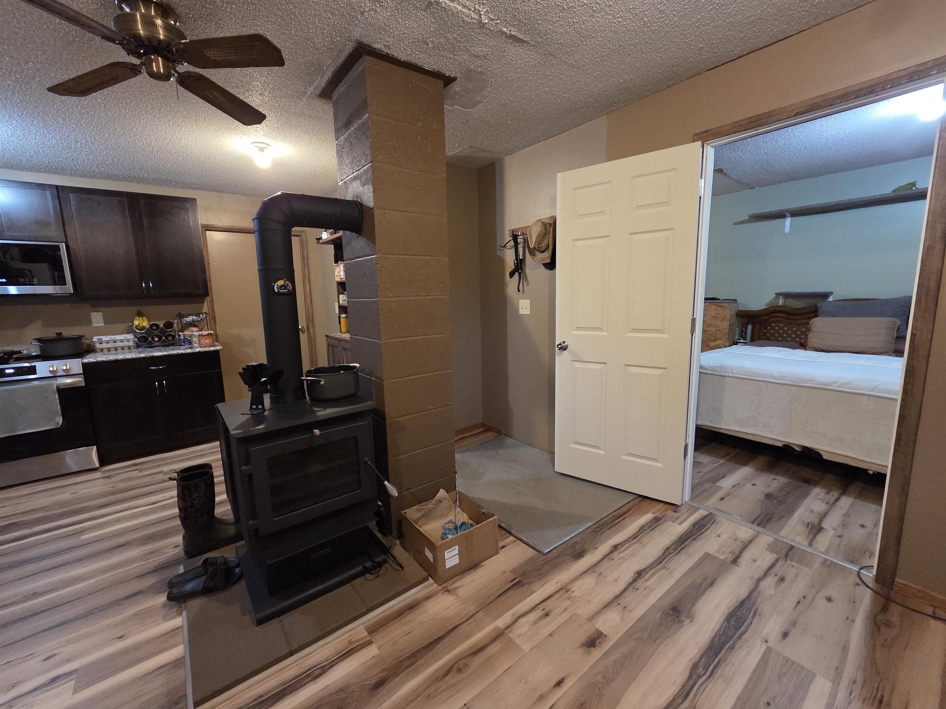 6821 Barrett Road Chisholm, MN 55719 - Photo 6 of 34 Living area with a textured ceiling, ceiling fan, light wood finished floors, and a wood stove