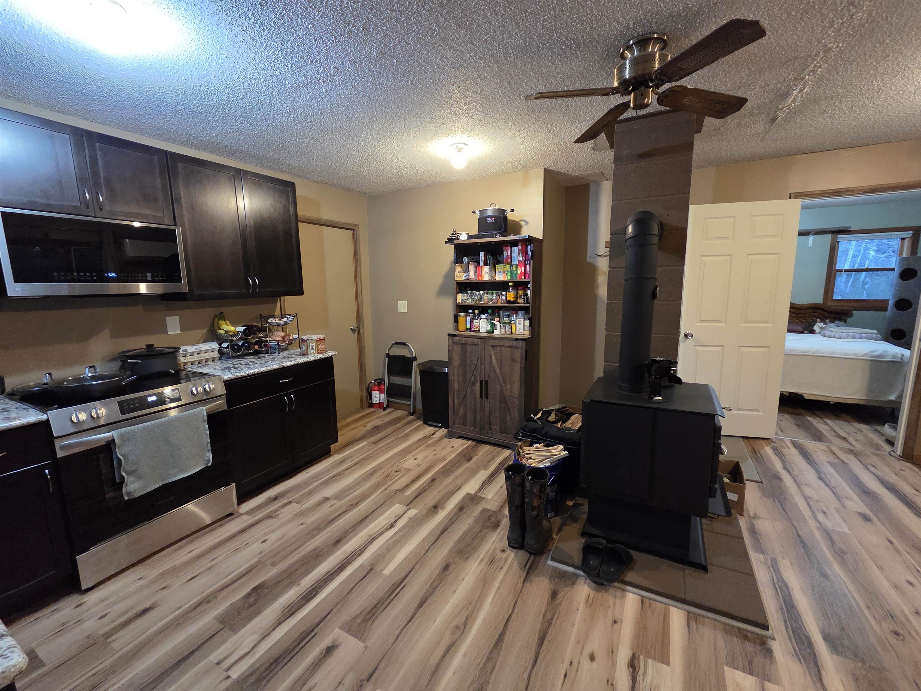 6821 Barrett Road Chisholm, MN 55719 - Photo 7 of 34 Kitchen with a wood stove, light countertops, a textured ceiling, appliances with stainless steel finishes, and light wood-type flooring