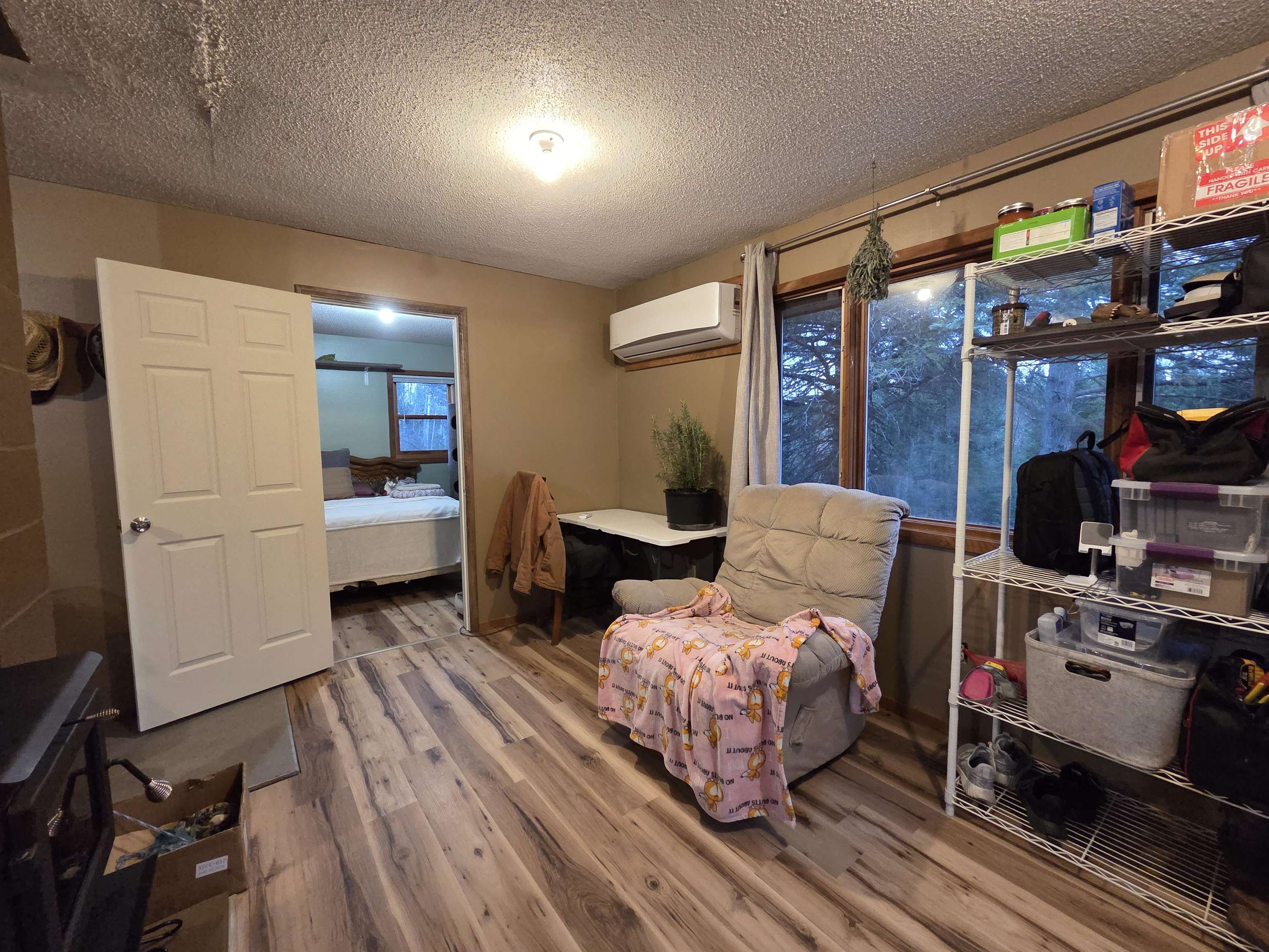 6821 Barrett Road Chisholm, MN 55719 - Photo 8 of 34 Sitting room featuring light wood-style flooring, a textured ceiling, and a wall unit AC