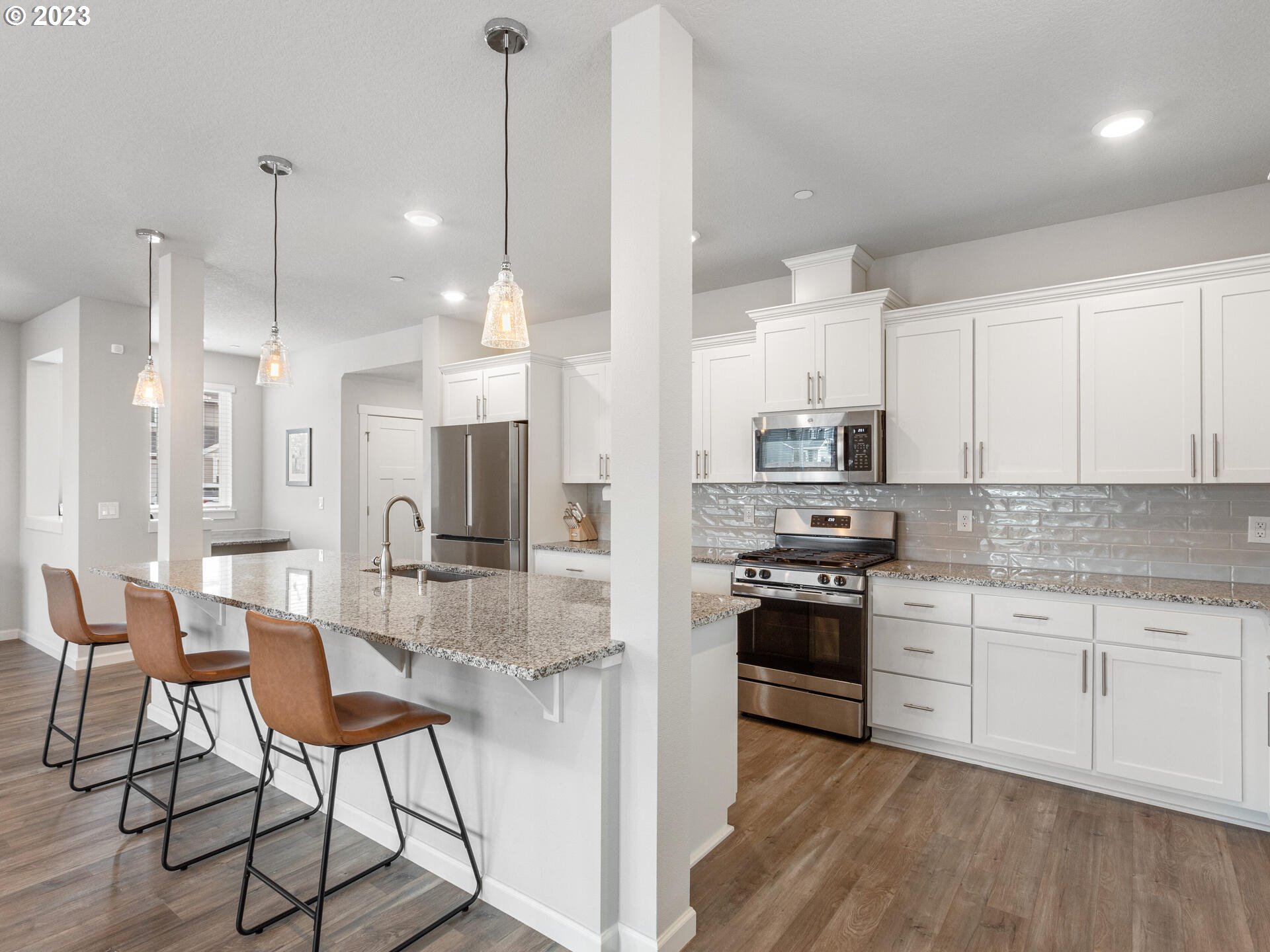 6852 North 89th Loop Camas, WA 98607 - Photo 8 of 38 a kitchen with stainless steel appliances kitchen island granite countertop a stove a sink and white cabinets with wooden floor