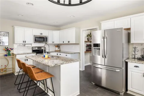 a kitchen with stainless steel appliances granite countertop a refrigerator a stove a sink a dining table and chairs