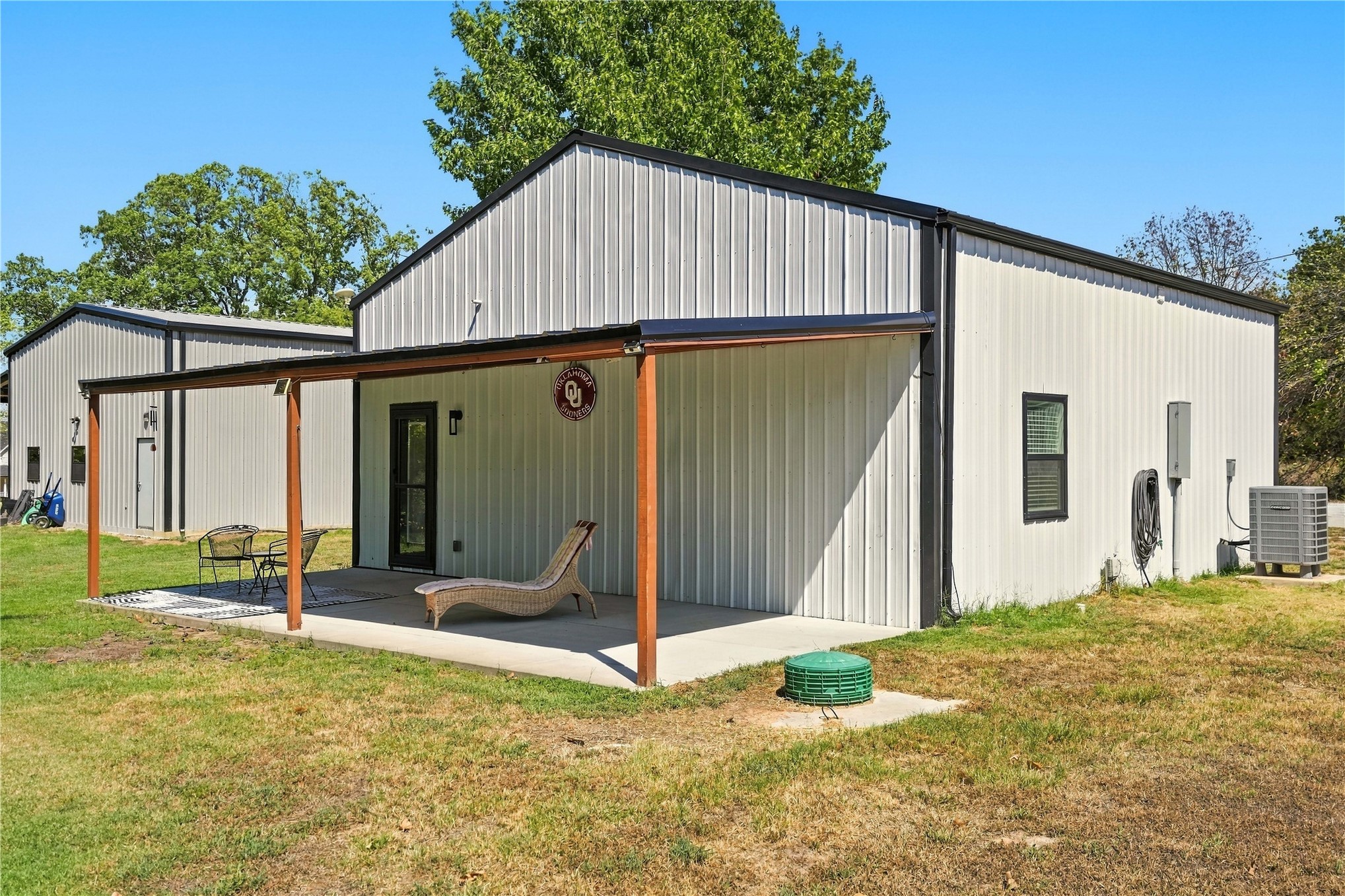 White corrugated metal siding with black trim, concrete patio, and a covered entryway