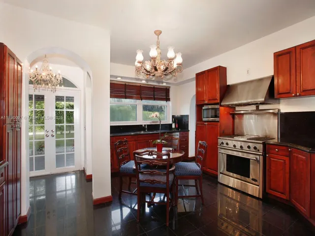 an empty room with wooden floor chandelier and windows