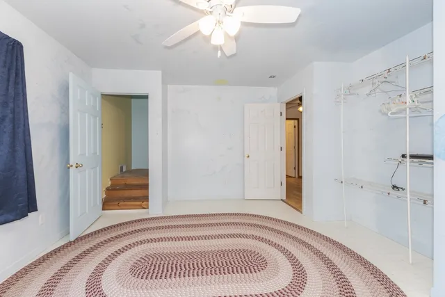 an empty room with ceiling fan and window