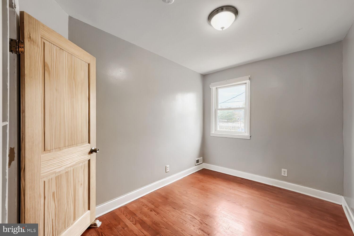 1014 Lyndhurst Street Baltimore, MD 21229 - Photo 17 of 29 an empty room with wooden floor and windows