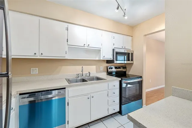 a kitchen with white cabinets and appliances