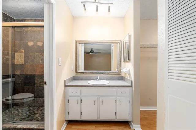 a bathroom with a granite countertop sink a toilet a mirror and shower