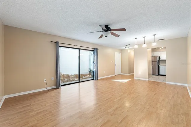 a view of an empty room with a window and wooden floor