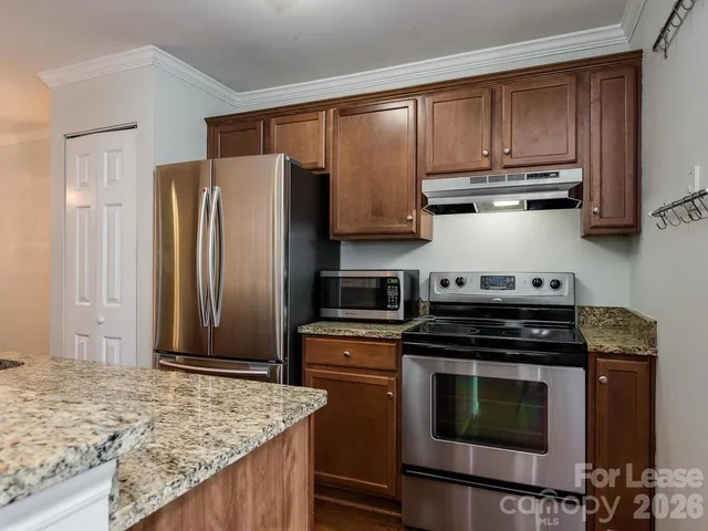 a kitchen with granite countertop wooden cabinets and stainless steel appliances