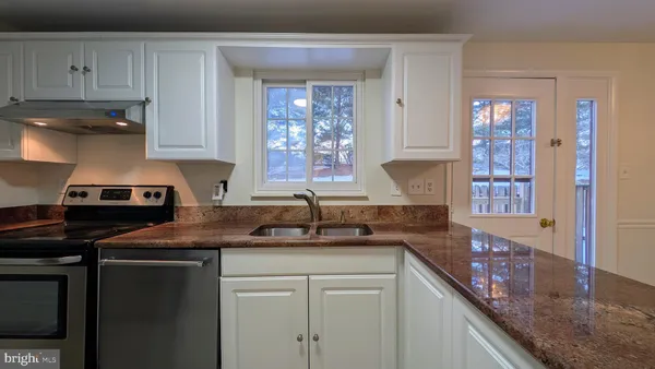 a kitchen with granite countertop a sink a stove and cabinets