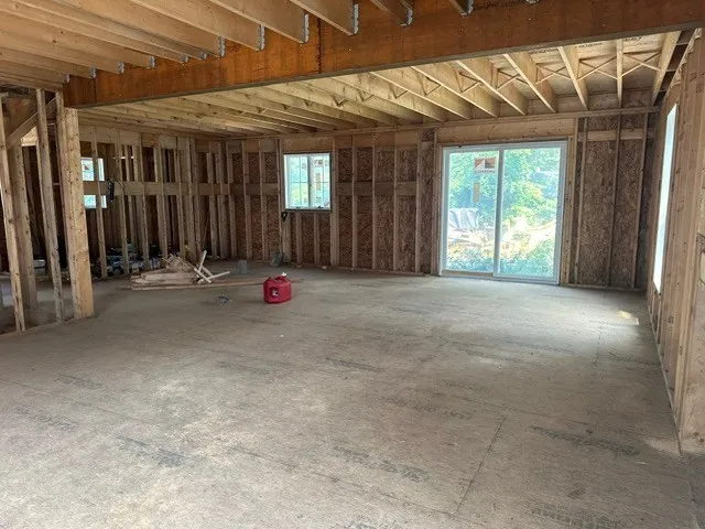 a view of an empty room with wooden floor and windows
