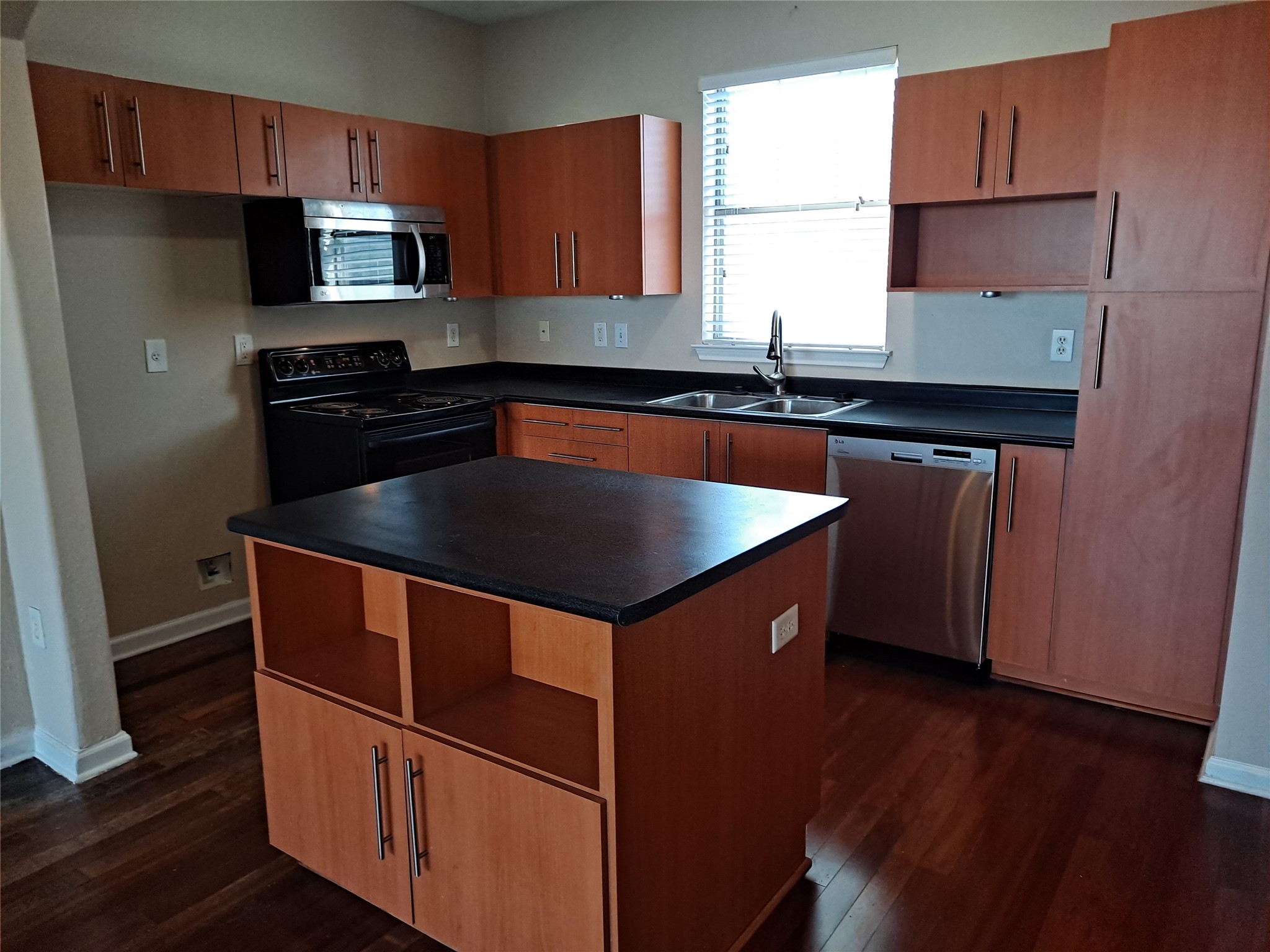 11203 Ranch Road 2222, Unit 2404 Austin, TX 78730 - Photo 5 of 28 Kitchen featuring open shelves, stainless steel appliances, dark countertops, wood finish cabinets, and a center island