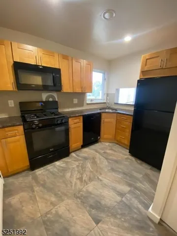 a kitchen with granite countertop a refrigerator stove top oven a sink and dishwasher