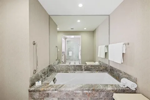 a bathroom with a granite countertop tub sink and mirror