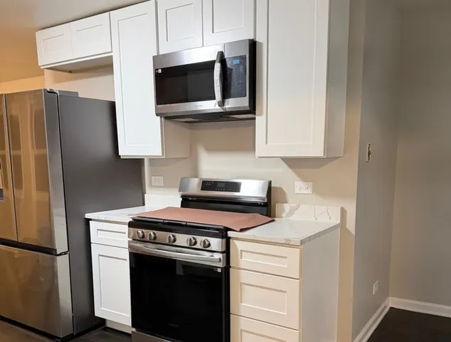 a kitchen with stainless steel appliances granite countertop a stove a microwave and a refrigerator