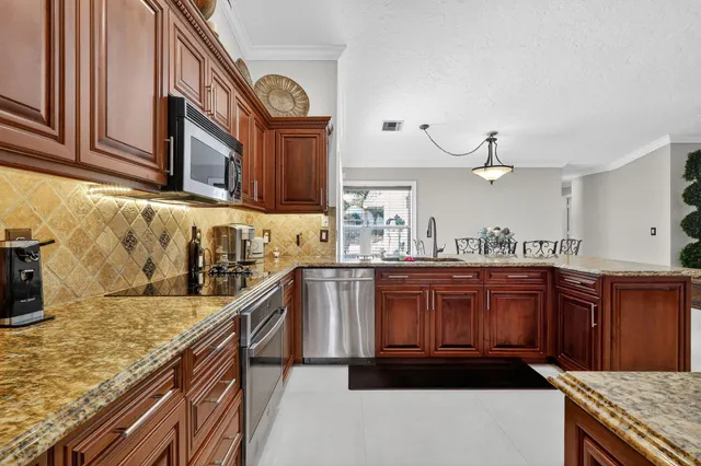 a kitchen with stainless steel appliances granite countertop a kitchen island a refrigerator a stove and a sink