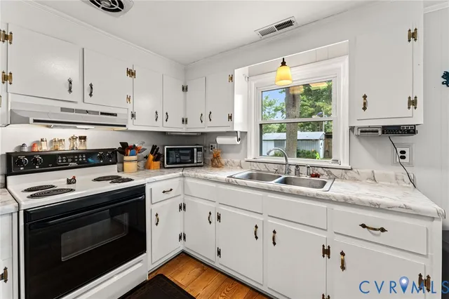 a kitchen with granite countertop a sink stainless steel appliances white cabinets and a window