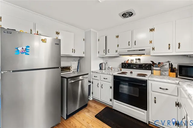 a kitchen with stainless steel appliances a refrigerator stove and white cabinets