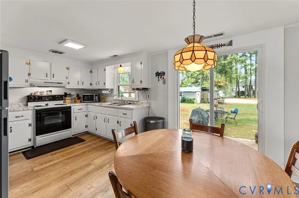 a kitchen with stainless steel appliances a white wooden cabinets a stove a sink and a large window with wooden floor