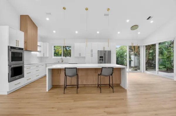 a large kitchen with stainless steel appliances kitchen island a large counter top and a floors