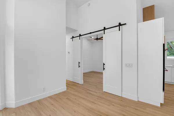 a view of an empty room with wooden floor and windows