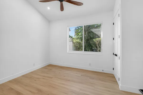 a view of empty room with wooden floor and fan