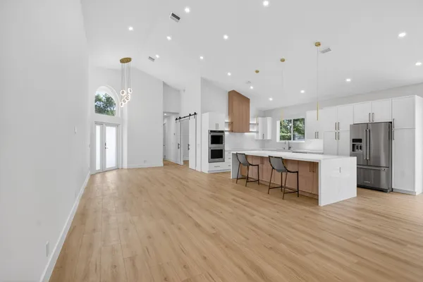 a large kitchen with stainless steel appliances kitchen island a large counter top and a refrigerator