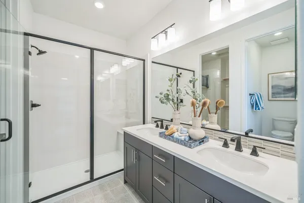 a bathroom with a double vanity sink mirror and shower