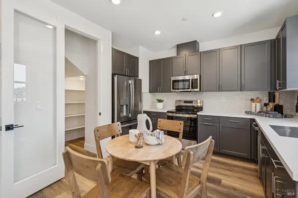 a kitchen with stainless steel appliances granite countertop a stove a sink a microwave a refrigerator with a dining table and chairs