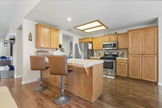 a kitchen with stainless steel appliances granite countertop a refrigerator a stove a sink dishwasher and white cabinets with wooden floor