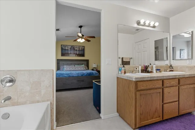 a bathroom with a double vanity sink a mirror and a bathtub