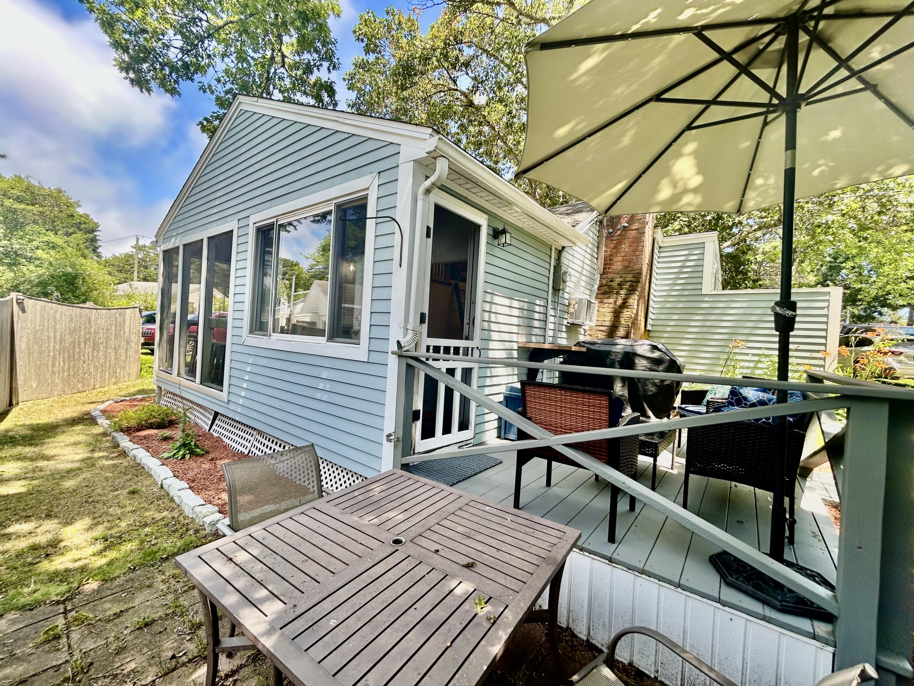 262 Old Wharf Road, Unit U67 Dennis Port, MA 02639 - Photo 36 of 54 a view of a patio with table and chairs with wooden floor and fence