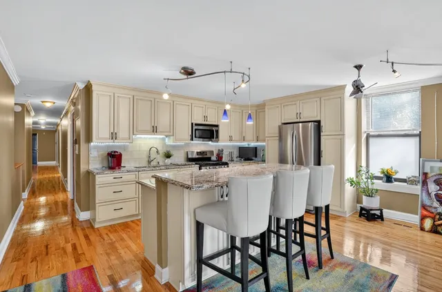 a kitchen that has a lot of cabinets a refrigerator and a dining table