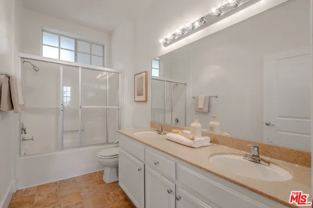 a bathroom with a double vanity sink toilet mirror and shower