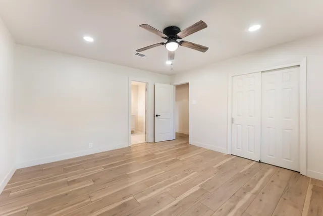 a view of empty room with wooden floor and kitchen