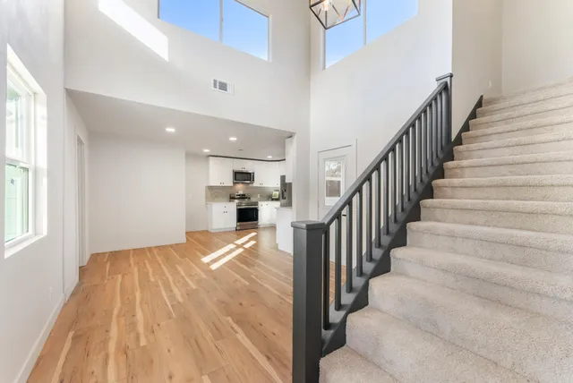 a view of empty room with wooden floor and kitchen