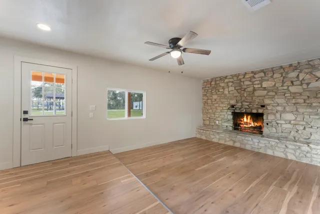an empty room with wooden floor and a ceiling fan