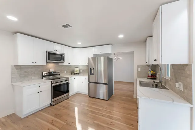 a view of an empty room with wooden floor and a ceiling fan