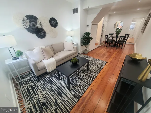 a living room with couches chairs and kitchen view with wooden floor