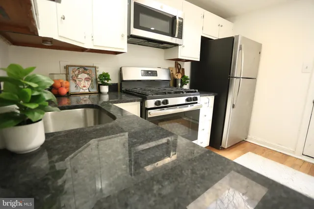 a kitchen with stainless steel appliances granite countertop a refrigerator a stove and a microwave