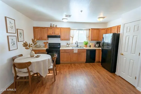 a kitchen with stainless steel appliances a refrigerator a sink dishwasher and a dining table with wooden floor