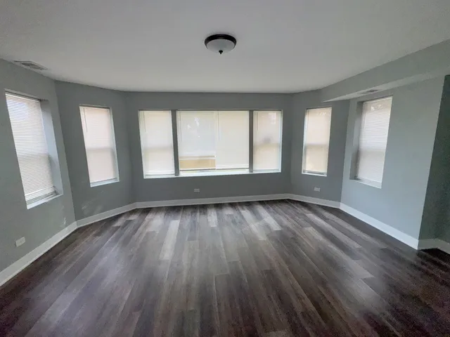 a view of an empty room with wooden floor and window