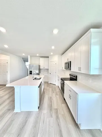 a large white kitchen with stainless steel appliances