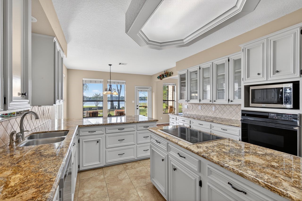 12626 Aries Loop Willis, TX 77318 - Photo 11 of 50 This spacious kitchen features elegant granite countertops, ample cabinetry, and modern appliances. It offers a bright, open feel with large windows providing natural light and a scenic view.