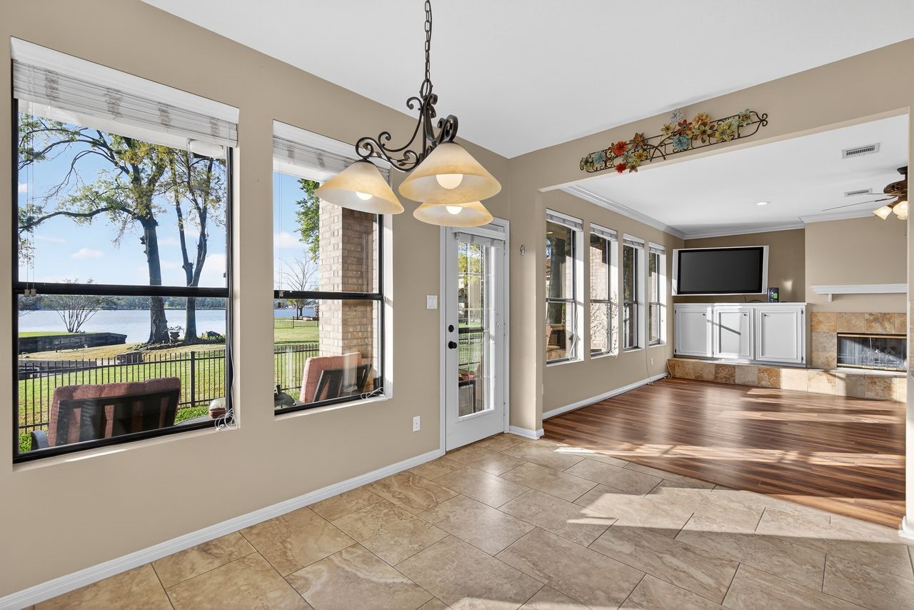 12626 Aries Loop Willis, TX 77318 - Photo 19 of 50 This bright and airy living space features large windows offering stunning lake views, a cozy fireplace, and elegant tile flooring. The open layout includes a seamless transition to a charming family area with built-in cabinetry, perfect for relaxation and entertainment.